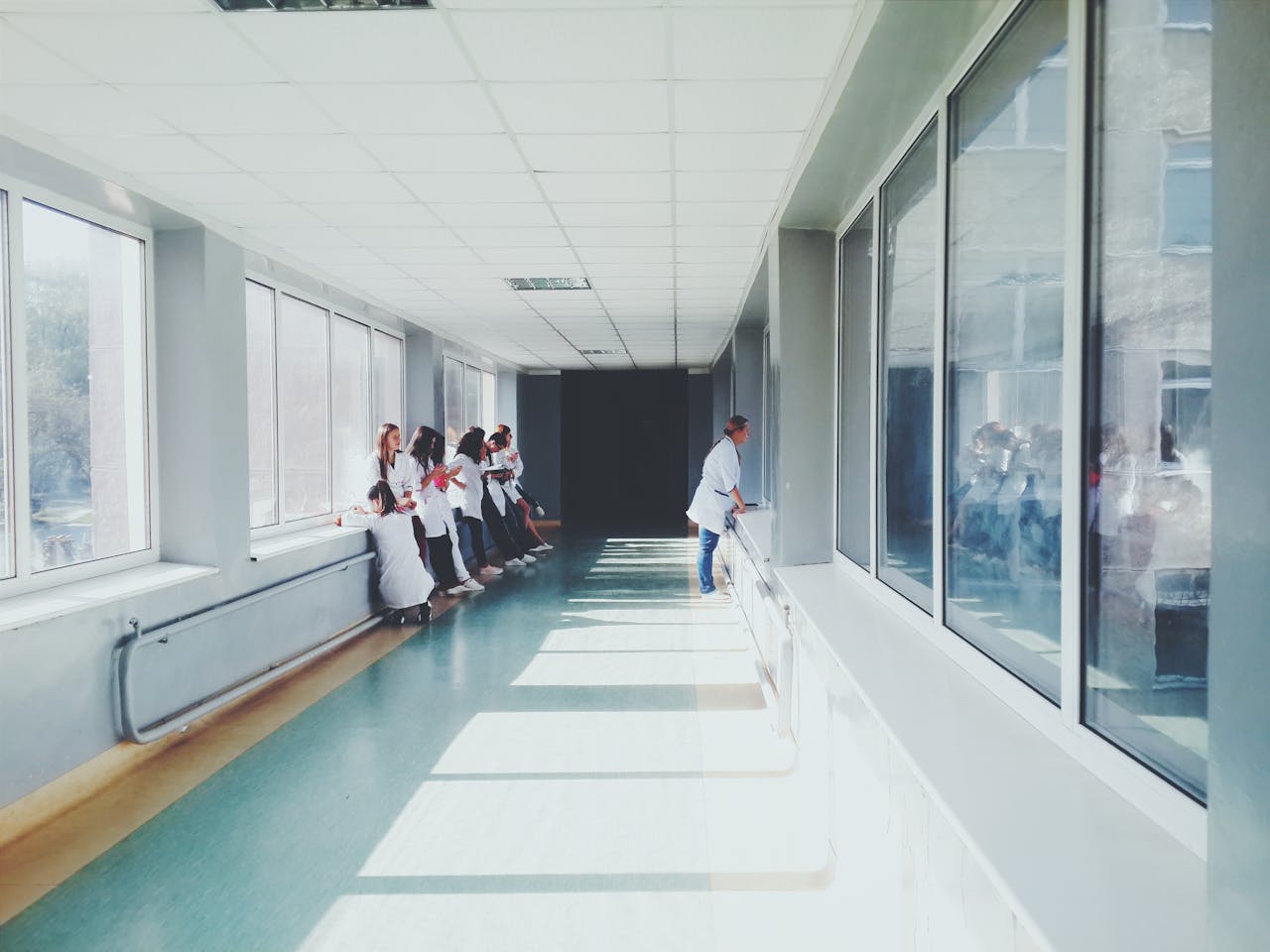 services-01 A brightly lit hospital hallway with medical staff in white coats, conveying a professional healthcare environment.